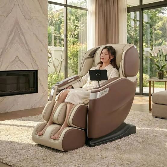 Woman in a bathrobe resting in a brown and cream full-body massage chair in a bright living room with a fireplace