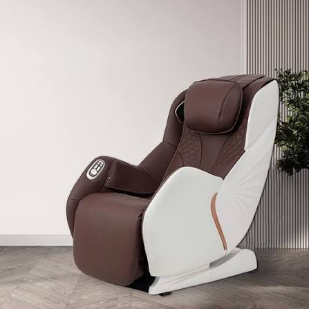Compact massage chair with brown upholstery and white side shell beside a plant
